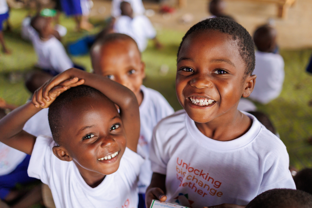 Children in Unlocking Big Change t-shirts smile at the camera.